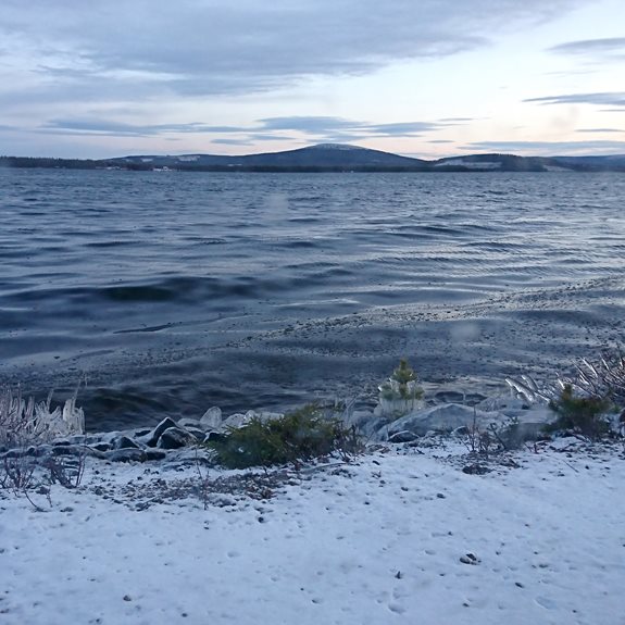 En mörk sjö med berg i bakgrunden.