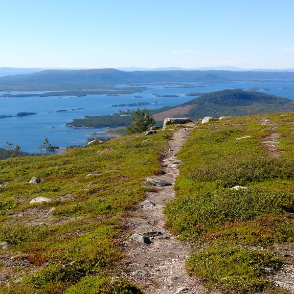 En fjällstig med en sjö och berg i bakgrunden.